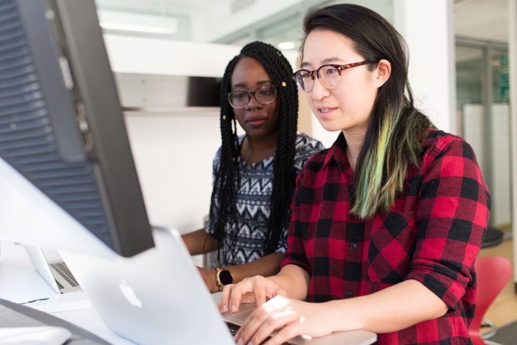 Two women are working on a computer.