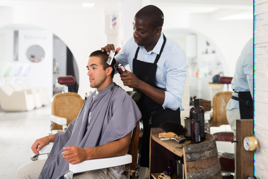 A barber is cutting the hair of a man.